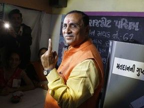 Gujarat Chief Minister Vijay Rupani shows his inked finger after casting his vote during first phase of Gujarat state assembly election in Rajkot, India, Saturday, Dec. 9, 2017. Results of the elections will be declared on Dec. 18.
