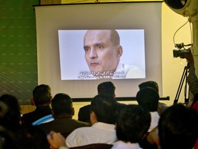 FILE - In this March 29, 2016, file photo, journalists look a image of Indian naval officer Kulbhushan Jadhav, who was arrested in March 2016, during a press conference by Pakistan's army spokesman and the Information Minister, in Islamabad, Pakistan. Pakistan's foreign ministry said on Sunday, Dec. 24, 2017, New Delhi has officially informed Islamabad that the wife and mother of Jadhav, who faces death penalty for espionage and sabotage are arriving in the capital for a meeting with him.