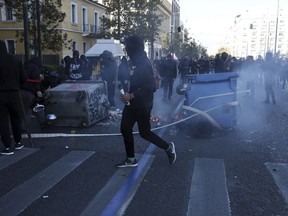 A hooded man holds a petrol bomb as other youths set up a barricade during a protest in central Athens, Wednesday, Dec. 6, 2017. Small groups of youths, their faces covered with scarves, have scuffled with police ahead of a high school students' demonstration to mark the ninth anniversary of the fatal police shooting of a teenager in Athens that sparked the worst rioting Greece had seen in decades.