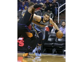 Memphis Grizzlies center Marc Gasol, right, drives to the basket past the defense of Phoenix Suns' Greg Monroe during the first half of an NBA basketball game Thursday, Dec. 21, 2017, in Phoenix.