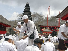 Hindu priests give holy water to worshipers during a prayer  at a temple located a few kilometers (miles) from the crater of the Mount Agung volcano in Karangasem, Bali, Indonesia, Sunday, Dec. 3, 2017. Authorities have told tens of thousands of people to leave an area extending 10 kilometers (6 miles) from the volcano as it belches volcanic materials into the air. Mount Agung's last major eruption in 1963 killed about 1,100 people.