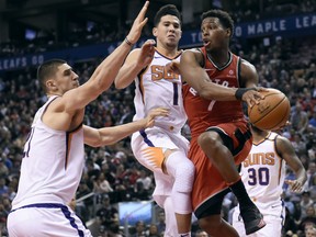 Phoenix Suns centre Alex Len (21) and Devin Booker (1) defend as Raptors guard Kyle Lowry looks to make a pass during second half NBA action in Toronto on Tuesday night.