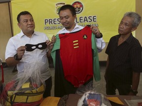 FILE - In this Monday, May 22, 2017, file photo, police officers show a costume confiscated in a raid on a gay sauna at North Jakarta police headquarters in Jakarta, Indonesia. An activist says an Indonesian court has sentenced eight men involved in running a gay club and sauna to two years in prison. They were among more than 140 men detained after a raid in May on what police said was a sex party at the Atlantis spa in Jakarta.