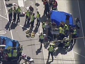 In this photo made video from the Australian Broadcasting Corp., emergency medical workers offer aid to victims struck by a vehicle, Thursday, Dec. 21, 20217, in Melbourne, Australia. Local media say over a dozen people have been injured after a car drove into pedestrians on a sidewalk in central Melbourne. (Australian Broadcast Corp. via AP)