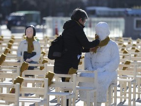 FILE - In this Wednesday, Dec. 27, 2017, file photo, a woman puts a scarf on a statue of a comfort woman sitting in a installation of empty chairs symbolizing the victims in Seoul, South Korea. South Korean President Moon Jae-in said Thursday the country's 2015 agreement with Japan to settle a decades-long impasse over Korean women forced into wartime sexual slavery was seriously flawed.