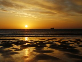 A ship passes across the horizon of the North Sea near Tynemouth beach, North Tyneside, England at sunrise Tuesday April 19, 2016.