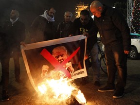 Palestinian protesters burn posters of US President Donald Trump in Bethlehem on December 5, 2017.