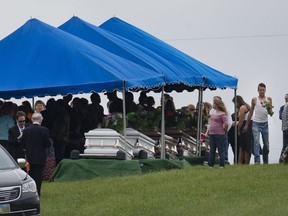 FILE – In this May 3, 2016, file photo, mourners gather during funeral services at Scioto Burial Park in McDermott, Ohio, around caskets for six of the eight members of the Rhoden family found shot April 22, 2016, at four properties near Piketon, Ohio. A divided Ohio Supreme Court on Thursday, Dec. 14, 2017, rejected requests for the unredacted autopsy reports from the unsolved slayings.