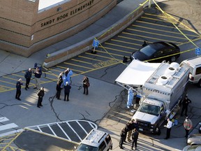 FILE - In this Dec. 14, 2012, file photo, officials stand outside of Sandy Hook Elementary School in Newtown, Conn. A 2014 report by the Office of Connecticut Child Advocate concluded that gunman Adam Lanza's actions were not directly caused by his psychiatric problems, but it noted that his mother rejected psychologists' recommendations that her son should be medicated and undergo treatment for anxiety and other conditions. Five years after the massacre, efforts to improve mental health care for young people have had mixed results.