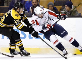 Boston Bruins' Brandon Carlo and Washington Capitals' Chandler Stephenson (18) battle for the puck during the first period of an NHL hockey game in Boston Thursday, Dec. 14, 2017.