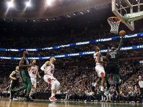 Boston Celtics guard Kyrie Irving goes in for a layup past Chicago Bulls' Kris Dunn during the first quarter of an NBA basketball game in Boston on Saturday, Dec. 23, 2017.