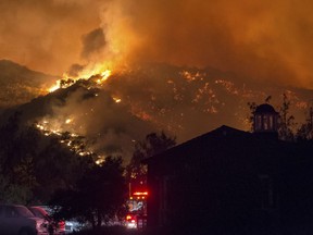 In this Sunday, Dec. 10, 2017, photo flames from a wildfire consume the mountainside near the Cate School campus in Carpinteria, Calif.
