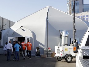 Crews work in front of the the city's new Temporary Bridge Shelter for the homeless Friday, Dec. 1, 2017, in San Diego. The first of three shelters opened Friday, which will eventually provide beds for up to 700 people, as the city struggles to control a homeless crisis gripping the region.