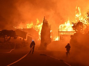 In this photo provided by the Ventura County Fire Department, firefighters work to put out a blaze burning homes early Tuesday, Dec. 5, 2017, in Ventura, Calif. Authorities said the blaze broke out Monday and grew wildly in the hours that followed, consuming vegetation that hasn't burned in decades.