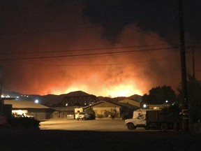 Flames from a wildfire loom up over a neighborhood in Santa Paula, Calf., Monday, Dec. 4, 2017. Ventura County fire officials say the blaze broke out Monday east of Santa Paula, a city of 30,000 people about 60 miles northwest of downtown Los Angeles. Powerful winds are pushing the blaze west toward the city along Highway 150, which is shut down.