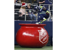 Seattle Seahawks cornerback Justin Coleman (28) leaps into The Salvation Army kettle after returning a Dallas Cowboys' Dak Prescott interception for a touchdown in the second half of an NFL football game, Sunday, Dec. 24, 2017, in Arlington, Texas.