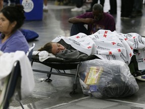 FILE - In this Aug. 29, 2017 file photo, people rest at the George R. Brown Convention Center that was been set up as a shelter operated by the Red Cross for evacuees escaping the floodwaters from Tropical Storm Harvey in Houston, Texas. The groups helping to rebuild on the Texas Gulf Coast after Hurricane Harvey have collected close to $1 billion in donations. Of the $853 million raised by major groups involved in the recovery, the most money has been collected by the Red Cross, which said this month that it's raised $493 million for Harvey relief.