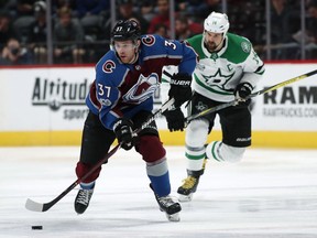 Colorado Avalanche left wing J.T. Compher, front, pick up a loose puck in front of Dallas Stars left wing Jamie Benn during the first period of an NHL hockey game Sunday, Dec. 3, 2017, in Denver.