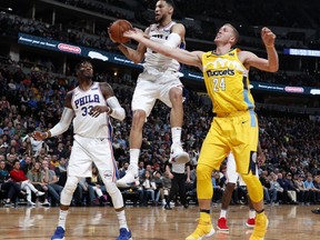 Philadelphia 76ers guard Ben Simmons, center, pulls in a rebound in front of forward Robert Covington, left, and Denver Nuggets center Mason Plumlee in the first half of an NBA basketball game Saturday, Dec. 30, 2017, in Denver.