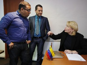In this Nov. 3, 2017 photo, Venezuela's ousted and exiled chief prosecutor Luisa Ortega, right, talks to fellow exiled prosecutors Pedro Lupera, center, and Zair Mundaray at their temporary office in Bogota, Colombia. Almost immediately after arriving in Bogota, Lupera and the others working to oust Venezuelan President Nicolas Maduro were welcomed by U.S. law enforcement agents and prosecutors pursuing charges against Venezuelan leaders, as well as Treasury Department officials running the Trump administration's sanctions program against Venezuela.