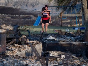 Kelsey Thorne holds her daughter Nevaeh Porter, 8, as they both cry while viewing the remains of their home where they lived with her parents that was destroyed by wildfire on the Ashcroft First Nation, near Ashcroft, B.C., late Sunday July 9, 2017.