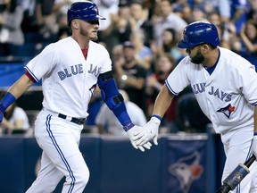 Toronto Blue Jays third baseman Josh Donaldson (20) celebrates his solo home run with teammate Kendrys Morales during first inning AL MLB baseball action against the Tampa Bay Rays, in Toronto on Wednesday, August 16, 2017. Rogers Communications Inc. (TSX:RCI.B) is reportedly considering the sale of such assets as baseball's Toronto Blue Jays and a stake in media company Cogeco Inc. (TSX:CCA) to free up capital for other investments.THE CANADIAN PRESS/Nathan Denette