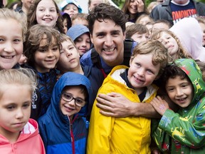 Prime Minister Justin Trudeau poses for a photograph with kids after kayaking on the Niagara River in Niagara-on-the Lake, Ont., on Monday, June 5, 2017. Trudeau was promoting World Environment Day. One year ago, Trudeau got eight provinces and all three territories to agree to put a price on pollution as part of a national climate change plan.