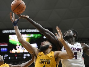 Connecticut's David Onuorah, right, grabs a rebound over the head of Coppin State's Chad Andrews-­Fulton, left, during the first half of an NCAA college basketball game, Saturday, Dec. 9, 2017, in Storrs, Conn.