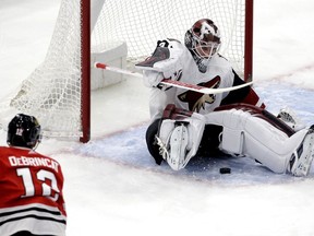 Arizona Coyotes goalie Scott Wedgewood, right, saves a shot by Chicago Blackhawks right wing Alex DeBrincat during the first period of an NHL hockey game Sunday, Dec. 10, 2017, in Chicago.
