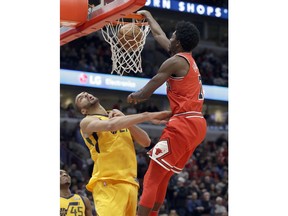 Chicago Bulls guard Justin Holiday, right, dunks against Utah Jazz center Rudy Gobert during the first half of an NBA basketball game Wednesday, Dec. 13, 2017, in Chicago.