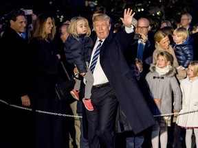 President Donald Trump holds a girl in his arm and waves to members of the media as he arrives at the White House in Washington, Saturday, Dec. 2, 2017, after traveling to New York for fundraising events.