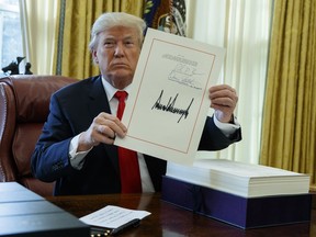 President Donald Trump shows off the tax bill after signing it in the Oval Office of the White House, Friday, Dec. 22, 2017, in Washington.
