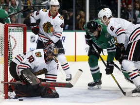 Chicago Blackhawks goalie Corey Crawford (50) stops a shot on goal as Dallas Stars center Martin Hanzal (10) and Chicago Blackhawks defenseman Connor Murphy (5) battle in front of the goal during the first period of an NHL hockey game in Dallas, Thursday, Dec. 21, 2017.