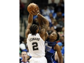 San Antonio Spurs forward Kawhi Leonard, left, has his shot blocked by Dallas Mavericks' Antonious Cleveland, right, in the first half of an NBA basketball game,Tuesday, Dec. 12, 2017, in Dallas.