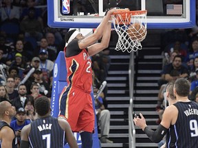 New Orleans Pelicans forward Anthony Davis, center, dunks between Orlando Magic guard Arron Afflalo (4), guard Shelvin Mack (7) and center Nikola Vucevic (9) during the first half of an NBA basketball game Friday, Dec. 22, 2017, in Orlando, Fla.
