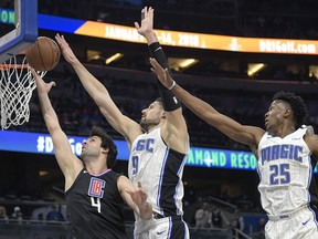 Los Angeles Clippers guard Milos Teodosic (4) has his shot blocked by Orlando Magic center Nikola Vucevic (9) as forward Wesley Iwundu (25) helps defend during the first half of an NBA basketball game Wednesday, Dec. 13, 2017, in Orlando, Fla.