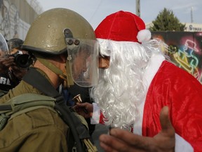 A Palestinian dressed as Santa Claus argues with an Israeli border police during a protest in the West Bank city of Bethlehem, Saturday, Dec. 23, 2017.