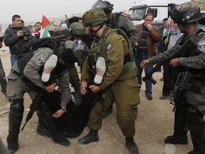 Israeli forces detain a Palestinian demonstrator during a protest demanding Israel to release Palestinian teenager Ahed Tamimi, near outside military prison near the West Bank city of Ramallah, Thursday, Dec. 28, 2017. Tamimi, a 17-year-old from the West Bank village of Nebi Saleh, was arrested last week by Israeli troops and faces charges of attacking soldiers.