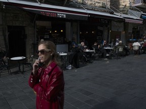 In this Sunday, Dec. 10, 2017 photo, a woman walks past a coffeeshop market trying to press the left arrow in Jerusalem. When President Donald Trump recognized contested Jerusalem as Israel's capital, he said he was simply acknowledging reality _ but failed to mention Palestinian residents, or 37 percent of the city's population. Despite such an omission and Israel's portrayal of Jerusalem as united, the city's de facto division between Jewish and Arab areas is apparent in the stark differences on the ground.