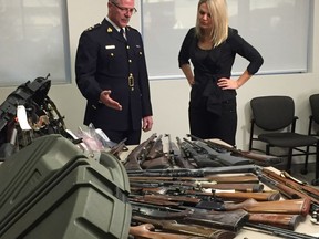 Red Deer RCMP Supt. Ken Foster and Red Deer Mayor Tara Veer look over seized guns in a handout photo. THE CANADIAN PRESS/HO-Red Deer RCMP MANDATORY CREDIT