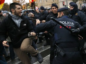 Catalan Mossos d'Esquadra officers scuffle with demonstrators outside the Lleida museum, in the west of Catalonia, Spain, Monday, Dec. 11, 2017. Spanish authorities take advantage of their direct powers over Catalonia to relocate 44 disputed art works from a museum in the Catalan city of Lleida to the neighbouring Spanish region of Aragon.
