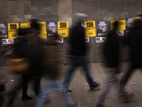 People walk past posters for the upcoming Catalan regional election in Barcelona, Spain, Monday, Dec. 18, 2017. The Catalan regional government was removed from office by Spain's national government in late October after regional lawmakers passed a declaration of independence that Spanish authorities deemed illegal.