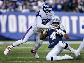 CORRECTS TO COWBOYS QUARTERBACK DAK PRESCOTT NOT ZAC DYSERT - Dallas Cowboys quarterback Dak Prescott (4) slides as he takes a hit from New York Giants outside linebacker Devon Kennard (59) during the first quarter of an NFL football game, Sunday, Dec. 10, 2017, in East Rutherford, N.J.