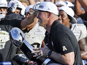 Central Florida head coach Scott Frost holds the winning trophy after defeating Memphis in the American Athletic Conference championship NCAA college football game, Saturday, Dec. 2, 2017, in Orlando, Fla. Central Florida won in overtime 62-55.