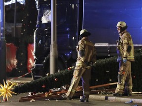 FILE - In this Dec. 19, 2016 file photo firefighters look at a toppled Christmas tree after a truck ran into a crowded Christmas market and killed several people in Berlin, Germany. Survivors and families of those killed in last year's Christmas market truck rampage in Berlin will meet with Chancellor Angela Merkel on Monday, Dec. 18, 2017 for the first time amid continued anger at German authorities' failure to stop the attack and handling of the aftermath.