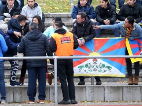 FILE - In this Nov. 18, 2017 file photo a Chinese spectator attempts to tear away a Tibetian flag which was raised by others in protest of China's politics regarding Tibet at the friendly match between TSV Schott Mainz and China's U20 team at the regional sports facility in Mainz, Germany. The German and Chinese soccer federations have abandoned a series of friendly games by the China under-20 team against fourth-tier clubs in Germany following a controversy over spectators displaying Tibetan flags.