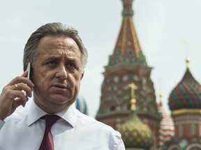 FILE - In this July 27, 2016 file photo Russia's Sports Minister Vitaly Mutko uses a mobile phone with the St.Bazil's Cathedral at the background, as he walks for a meeting with Russian President Vladimir Putin, in Moscow, Russia. On Tuesday, Dec. 5, 2017 IOC imposed a lifetime Olympic ban on Mutko.