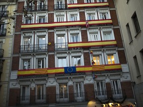 Spanish, Catalan and European Union flags hang on balconies of a building near the Supreme Court in Madrid, Spain, Tuesday, Dec. 19, 2017. Political parties for and against Catalonia's independence from Spain are making a final effort to convince voters as campaigning ends for a regional election seen as another litmus test on secession fervor.
