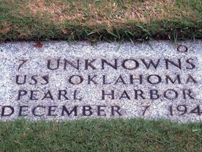 FILE - In this Dec. 5, 2012 file photo, a gravestone identifying the resting place of 7 unknowns from the USS Oklahoma is shown at the National Memorial Cemetery of the Pacific in Honolulu. The military says it has identified 100 sailors and Marines killed when the USS Oklahoma capsized during the Japanese bombing of Pearl Harbor 76 years ago. The milestone comes two years after the Defense POW/MIA Accounting Agency dug up nearly 400 sets of remains from a Hawaii to identify the men who have been classified as missing since the war. (AP Photo/Audrey McAvoy, File)