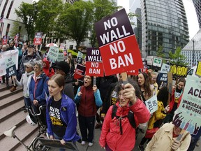 FILE - In this May 15, 2017, file photo, protesters wave signs and chant during a demonstration against President Donald Trump's revised travel ban outside a federal courthouse in Seattle. The fight over the latest version of President Donald Trump's travel ban that targets about 150 million potential travelers from Chad, Iran, Libya, North Korea, Somalia, Syria and Yemen returns to Washington state and Virginia. A three-judge panel of the 9th U.S. Circuit Court of Appeals hears arguments in Seattle on Wednesday, Dec. 6, followed by a full complement of 13 judges at the 4th Circuit in Richmond, Va., on Friday, Dec. 8.